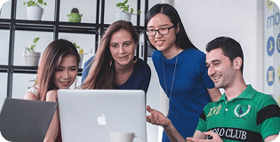 Four people looking at laptop and smiling